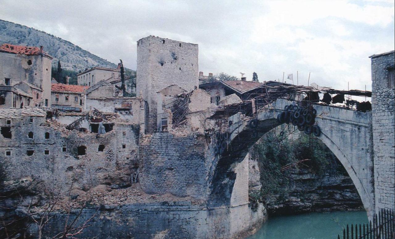 The 16th-century Ottoman bridge stands badly damaged after heavy shelling during the Bosnian War, weeks before its collapse, Oct. 1993, Mostar, Bosnia and Herzegovina. (Photo via Studio Kranzic)