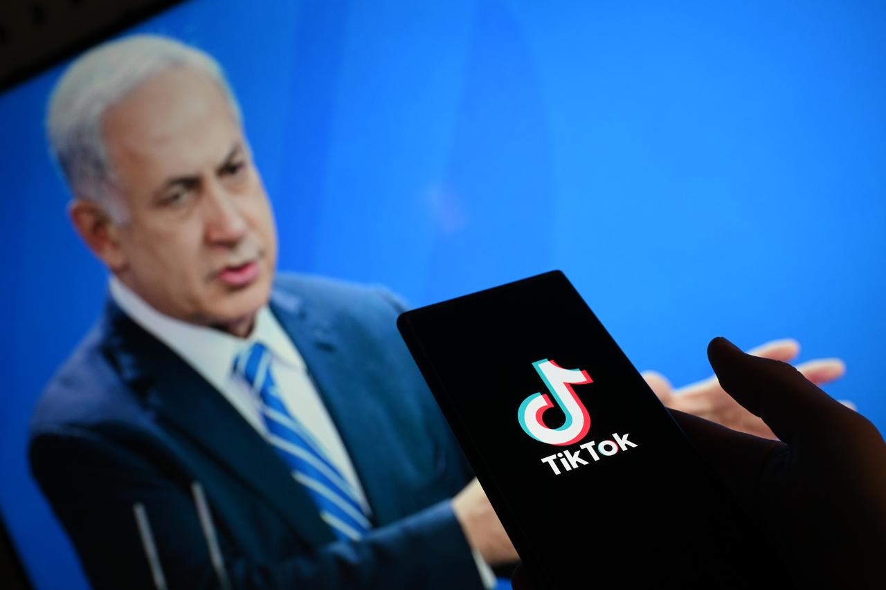The logo of TikTok is displayed on mobile phone screen in front of a computer screen displaying the photo of Israels Prime Minister Benjamin Netanyahu in Ankara, Türkiye on September 27, 2025. (AA Photo)