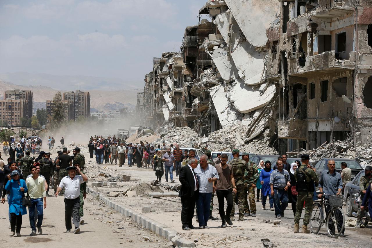 Siviller ve Assad yanlısı kuvvetler, 24 Mayıs 2018 başkentinin güney eteklerindeki Yarmuk Filistinli mülteci kampında yıkılan Thalateen Caddesi'nden aşağı iniyor. (AFP fotoğrafı)