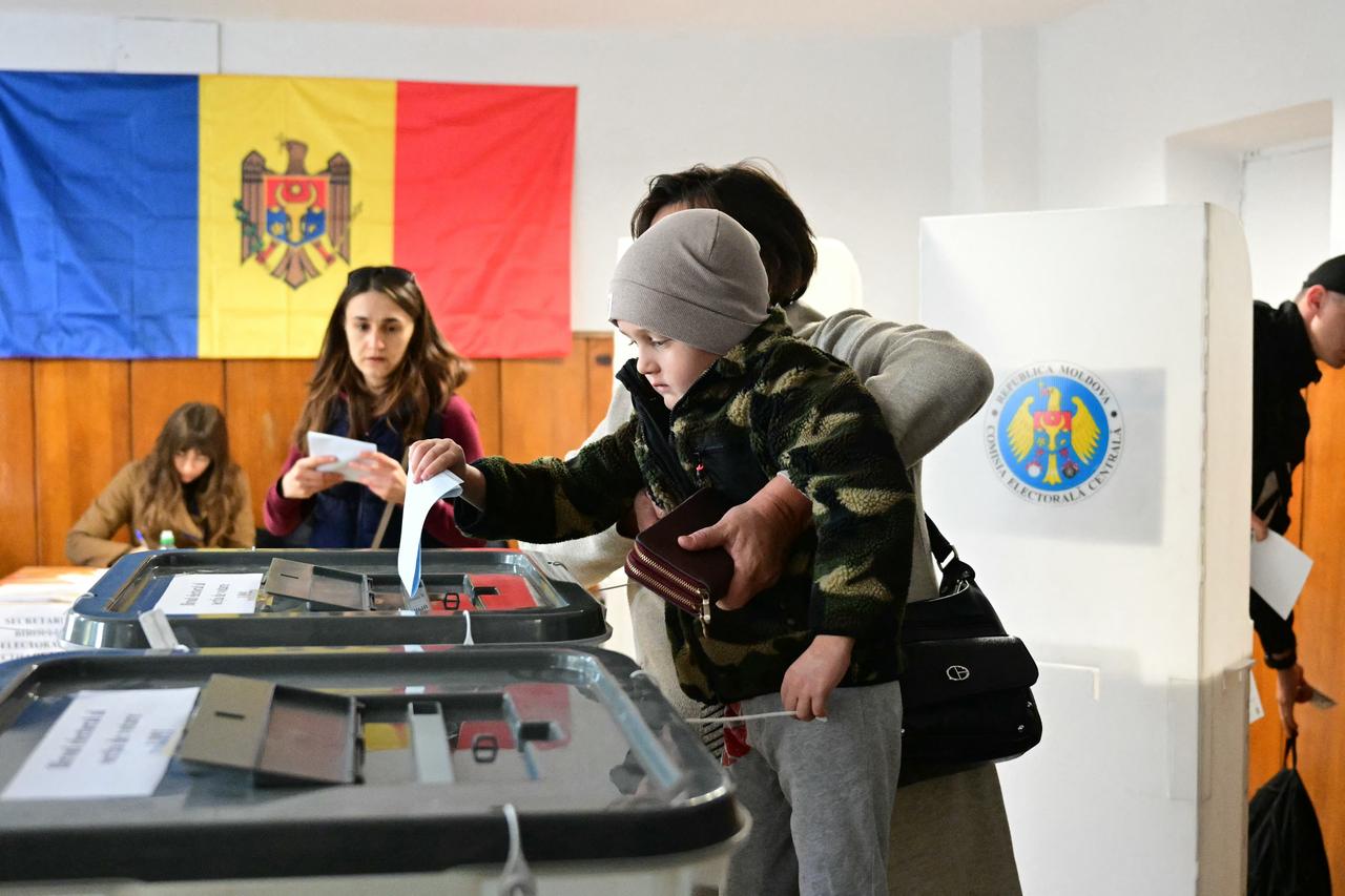 A woman holds her child as she casts her ballot in the parliamentary elections, in Chisinau, Moldova on Sept. 28, 2025. (AFP Photo)