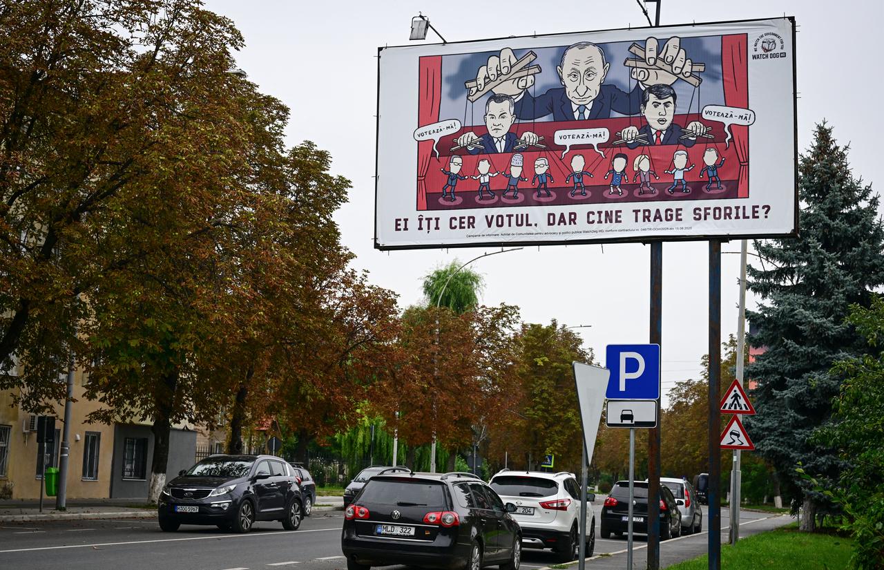 This photograph shows a caricature on a billboard bearing Russian President Vladimir Puting pulling the ropes of fugitives Ilan Shor (R) and Vladimir Plahotniuc (L) and reading "They ask for your vote" in Ungheni city Sept. 24, 2025. (AFP Photo)