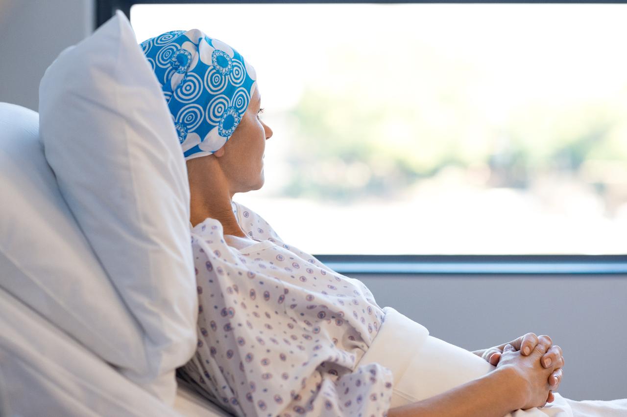 A cancer patient looks out of a hospital window while resting in bed. (Adobe Stock Photo)