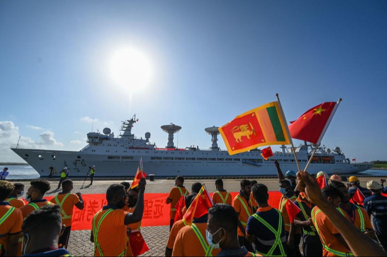Workers wave China's and Sri Lanka's national flags upon the arrival of China's research and survey vessel, the Yuan Wang 5 at Hambantota port on August 16, 2022. (AFP Photo)
