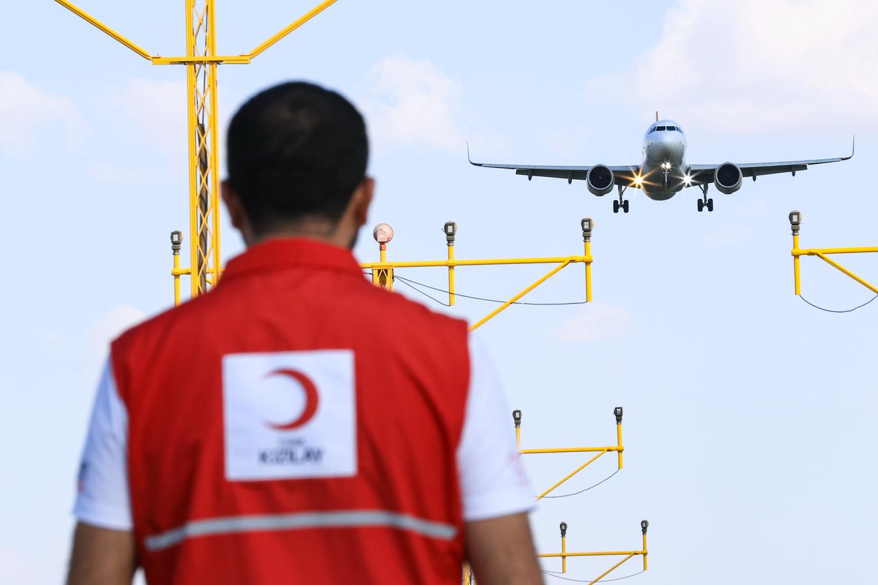 A Turkish Red Crescent worker is seen with a plane that looks to be landing at an unspecified location. (Photo via Turkish Red Crescent)