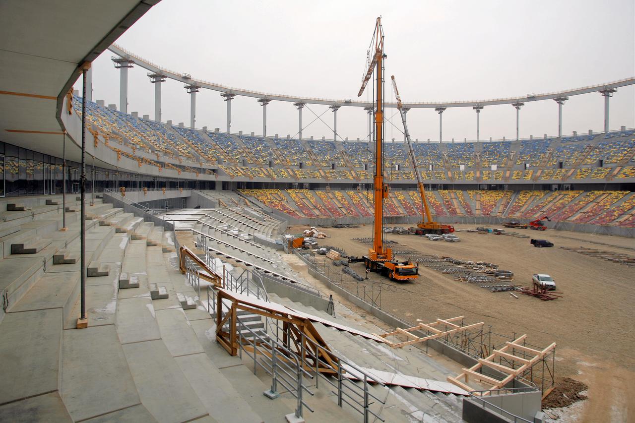 File photo shows cranes and workers at a stadium construction site. (Adobe Stock Photo)