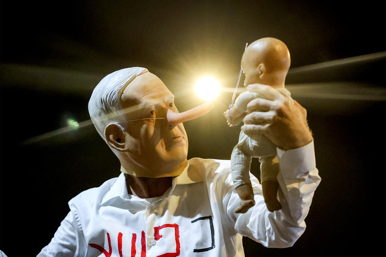 A demonstrator wearing a mask depicting Israeli Prime Minister Benjamin Netanyahu with an elongated nose, evoking the literary character Pinocchio, poses during an anti-government protest organized by the families of the Israel , outside the Defence Ministry headquarters in Tel Aviv, on August 23, 2025. ( AFP)