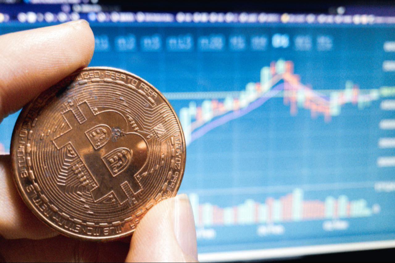 Photo illustration shows Bitcoin in hand with market charts in the background, accessed on July 11, 2025. (Adobe Stock Photo)
