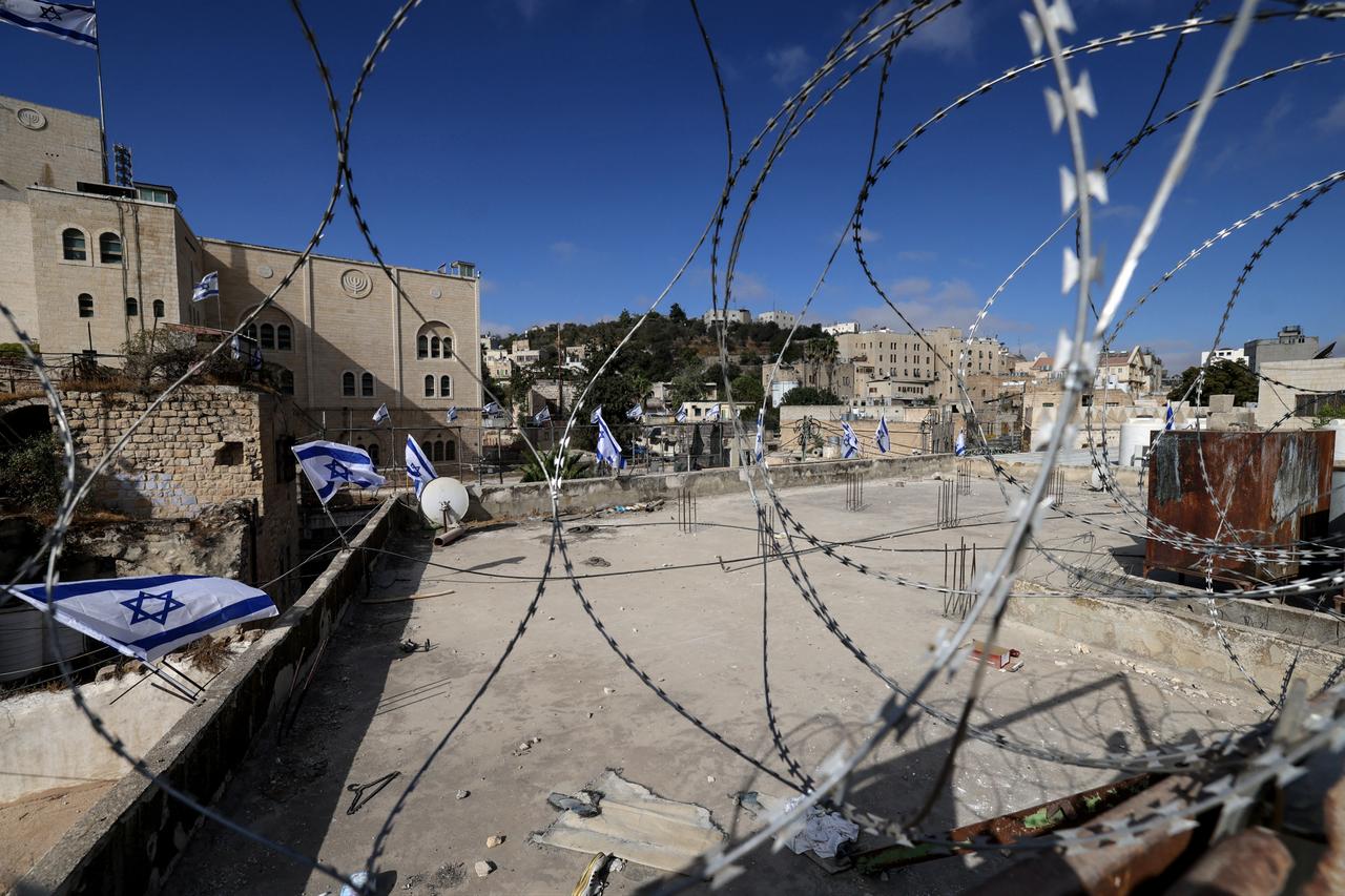 Metal wire encircles the roof of a house at the entrance of the Palestinian market in the old city of the occupied West Banks Hebron, September 3, 2025.  (AFP Photo)