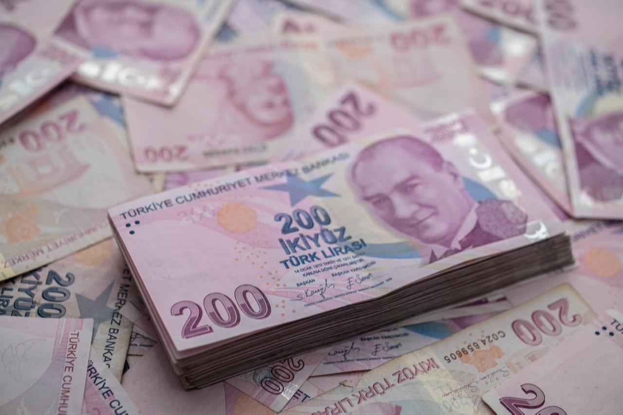 A file photo shows a stack of 200 Turkish lira banknotes placed on a scattered pile of various Turkish lira denominations. (Adobe Stock Photo)