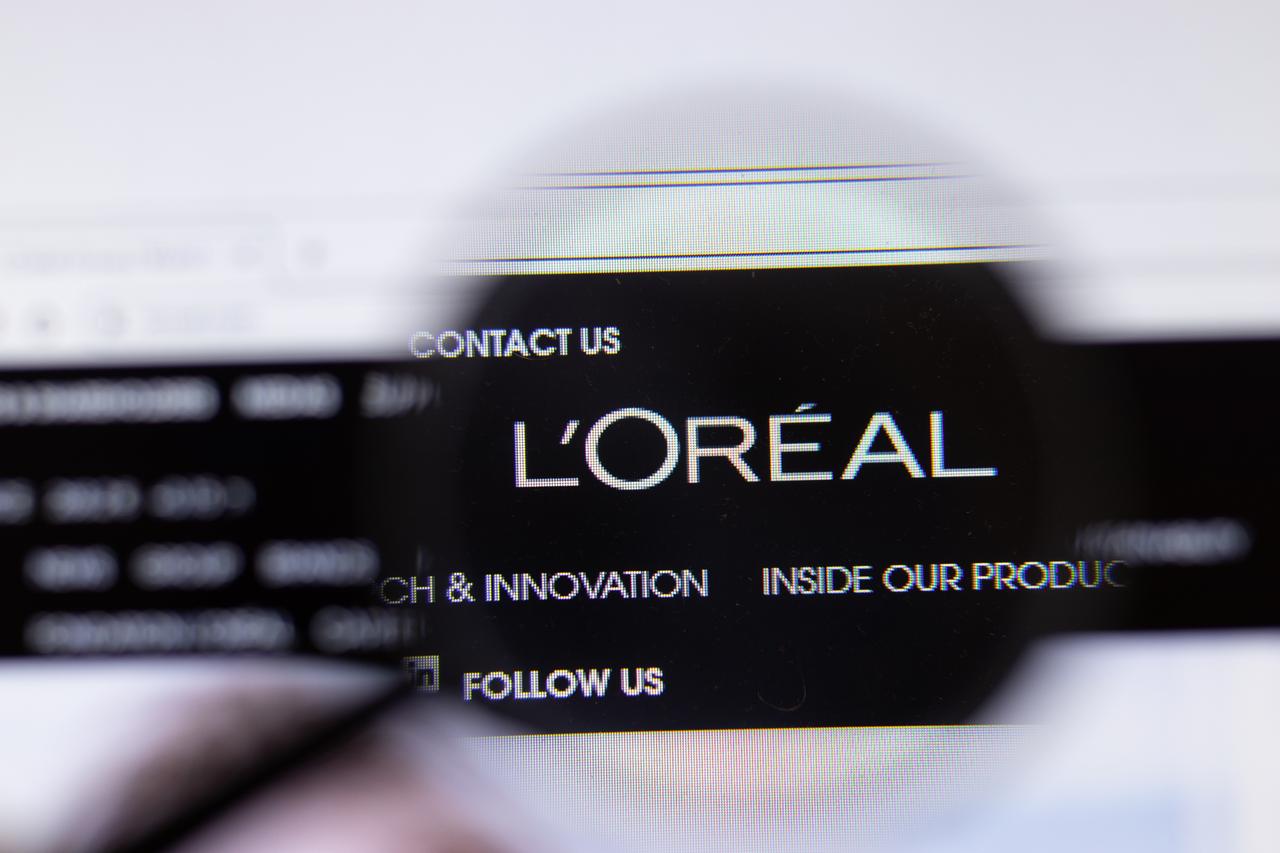 The logo of French cosmetics group L’Oreal is seen on a computer screen through a magnifying glass. (Adobe Stock Photo)