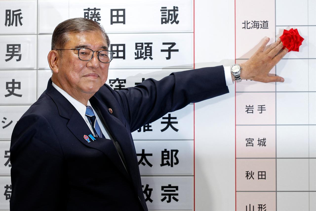 Japan's Prime Minister Shigeru Ishiba places a rose flower beside the name of an elected candidate in the upper house elections, at the vote counting centre in the Liberal Democratic Party (LDP) headquarters in Tokyo, Japan on July 20, 2025. (AFP Photo)