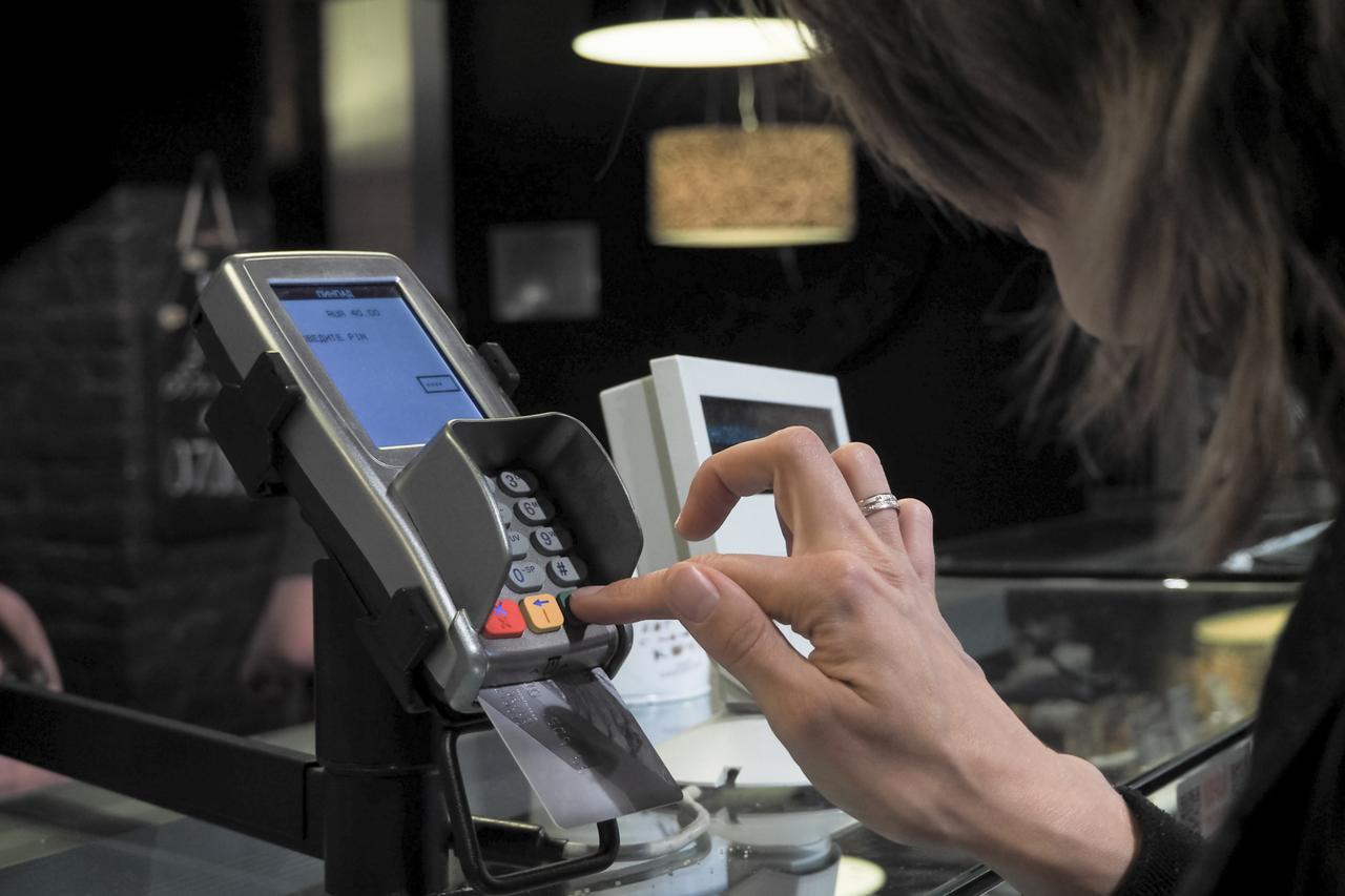 File photo shows a customer entering a PIN code at a card terminal. (Adobe Stock Photo)