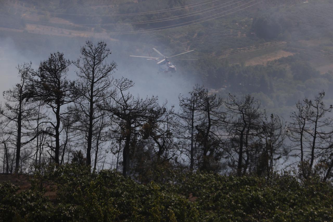 A helicopter carries water to extinguish fire as smoke from the fire area fills the sky while firefighters and Turkish General Directorate of Forestry teams continue their efforts to extinguish the fire that broke out in the forest area in Osmangazi district of Bursa, Türkiye on Sept. 05, 2025. (AA Photo)