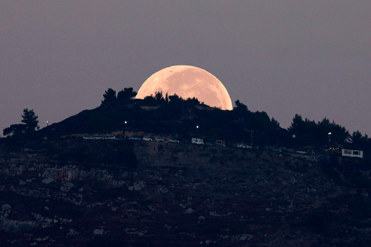 The full moon sets behind Mount Gerizim as pictured from Nablus in the occupied West Bank early on September 8, 2025. (AFP Photo)
