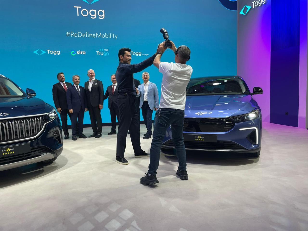 Actor Kenan Imirzalioglu gestures to the camera alongside Togg’s T10X and T10F models at IAA Mobility 2025 fair in Munich, Germany, Sept. 8, 2025. (Photo via turkiyegazetesi.com.tr)