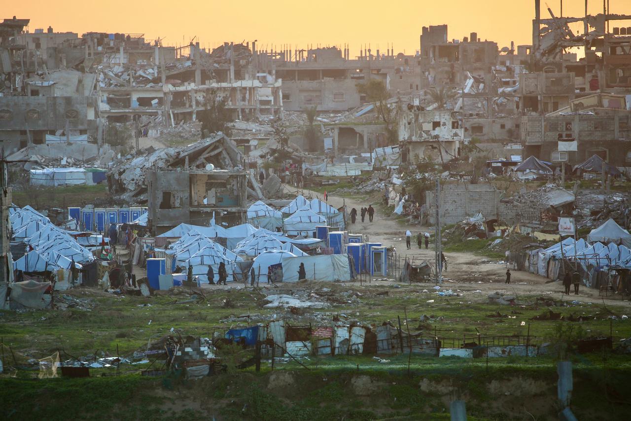 Palestinians walk past destroyed buildings in the Nuseirat refugee camp in the central Gaza Strip on December 31, 2025. (AFP Photo)