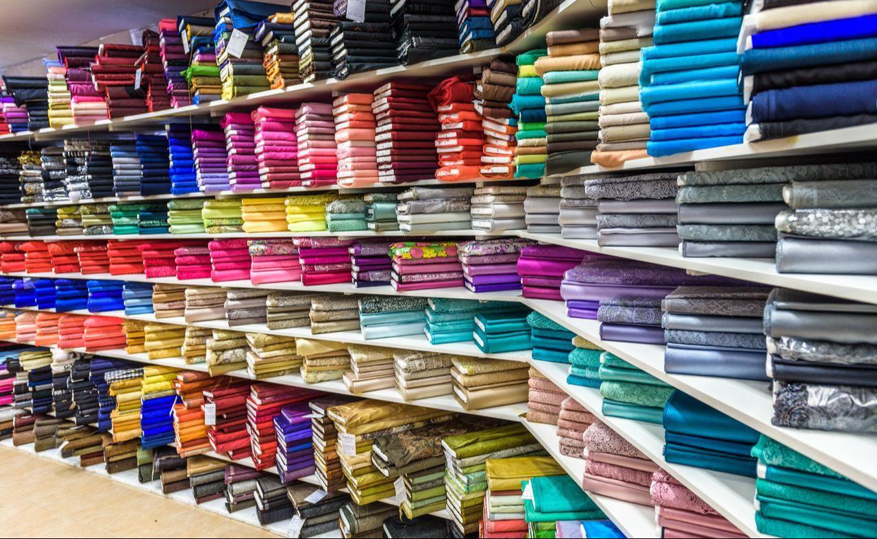 Stacks of colorful fabrics on display at a textile shop. (Adobe Stock Photo)