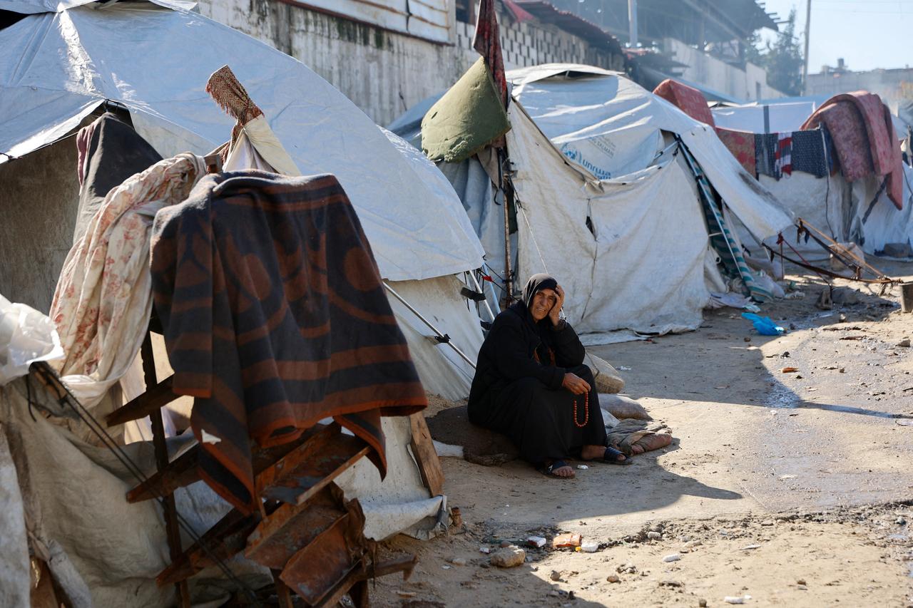 A displaced Palestinian woman rolls her pray beads as she sits outside a family tent shelter set-up in Gaza City on Jan. 11, 2026. (AFP Photo)