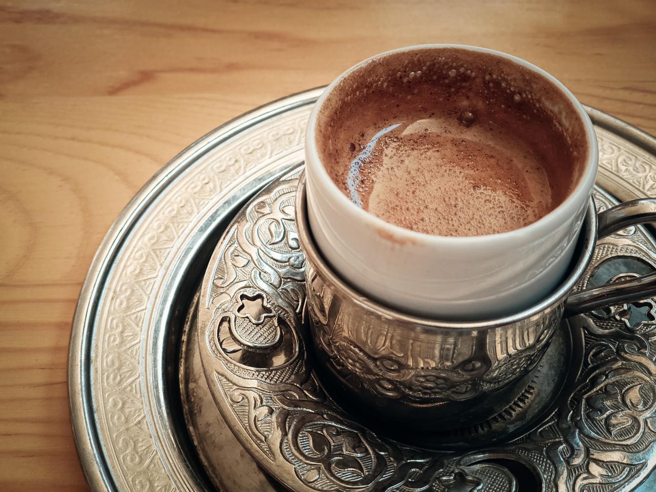 A cup of menengic coffee sits in a traditional metal holder on a patterned textile, served in Gaziantep, Türkiye, accessed on January 12, 2026. (Adobe Stock Photo)