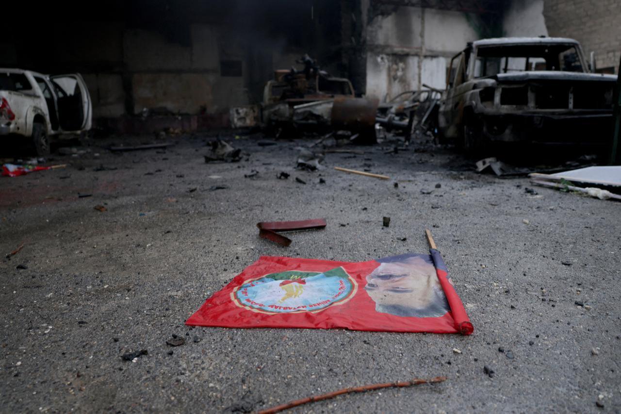 Destroyed vehicles and a flag with the image of jailed PKK ringleader Abdullah Ocalan, lies on the ground Sheikh Maqsoud neighbourhood, of the northern city of Aleppo, Jan. 11, 2026. (AFP Photo)