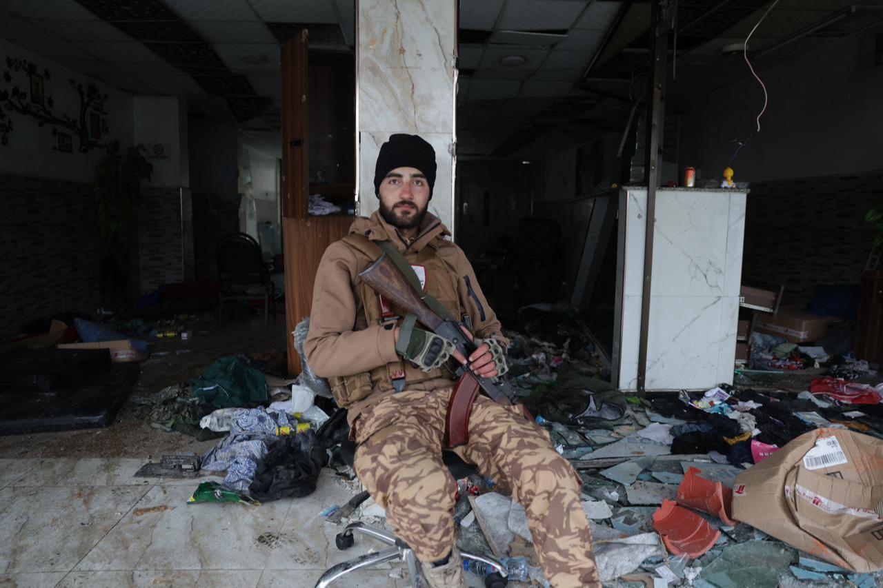 A Syrian security officer sits amongst strewn items and broken glass of the northern city of Aleppo, Jan. 11, 2026. (AFP Photo)