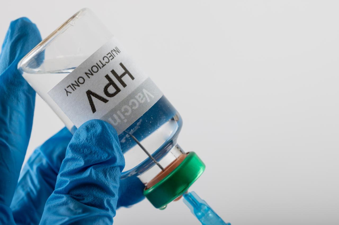 Composition of doctors gloved hands filling syringe from HPV vaccine vial. (Adobe Stock Photo)