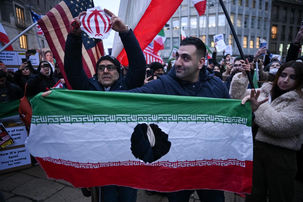An anti-Iranian regime protester holds the Islamic emblem of the national flag of the Islamic Republic of Iran after cutting it during a gathering outside the US Consulate in Milan, Italy on Jan. 13, 2026. (AFP Photo)