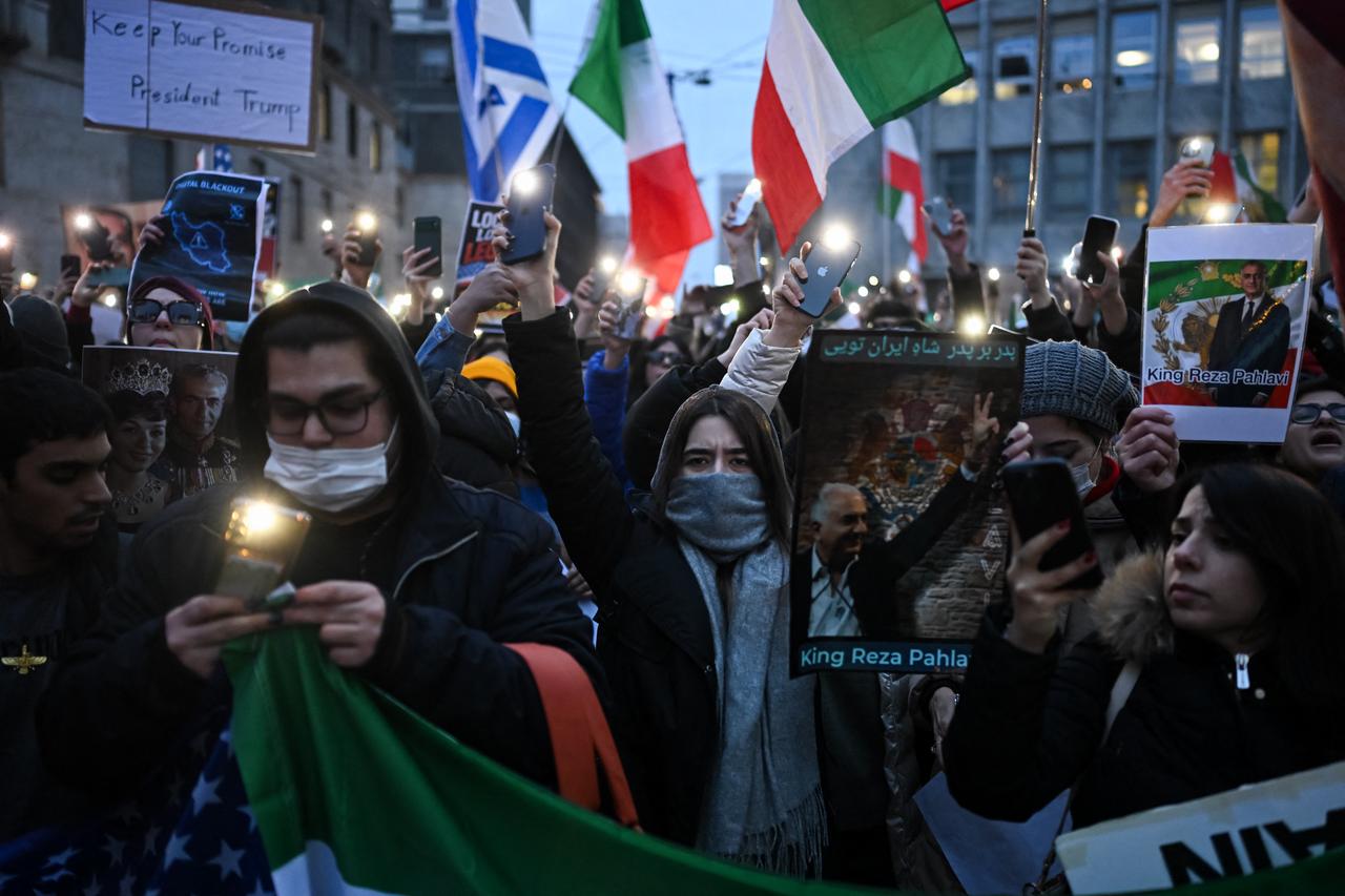 Anti-Iranian regime protesters light their cellphones and hold banners during a gathering outside the US Consulate in Milan, Italy on Jan. 13, 2026. (AFP Photo)