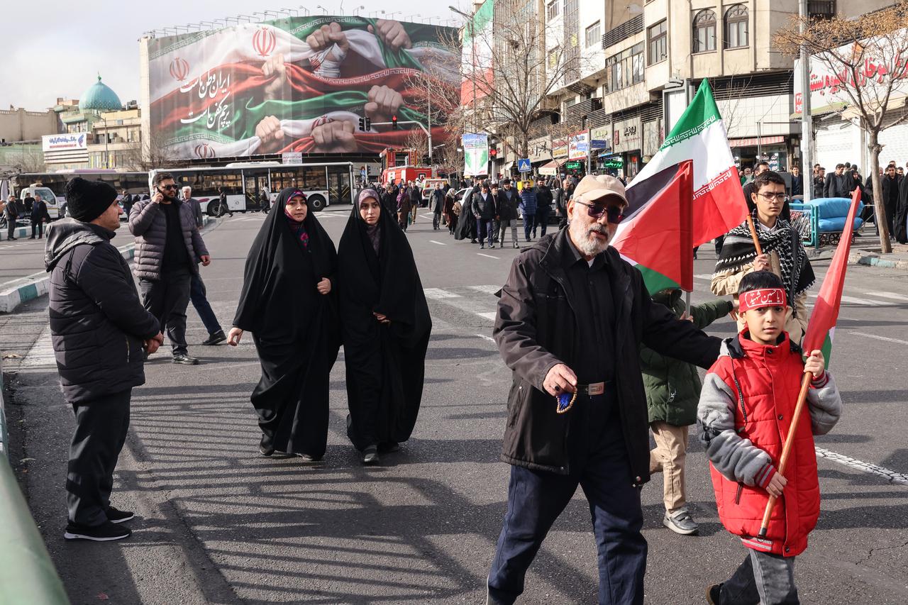 People walk past a large patriotic banner depicting the Iranian flag on Enghelab Square in Tehran on Jan. 14, 2026. (AFP Photo)