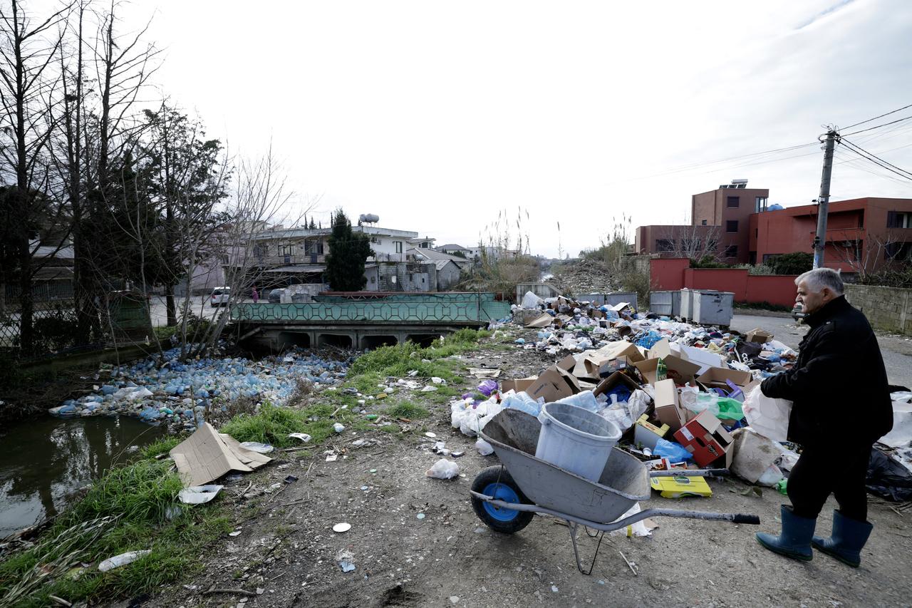 A man looks for goods to retrieve in a dumping area near plastic trash-filled floodwaters following heavy rains, in Durres, on Jan. 13, 2026. (AFP Photo)