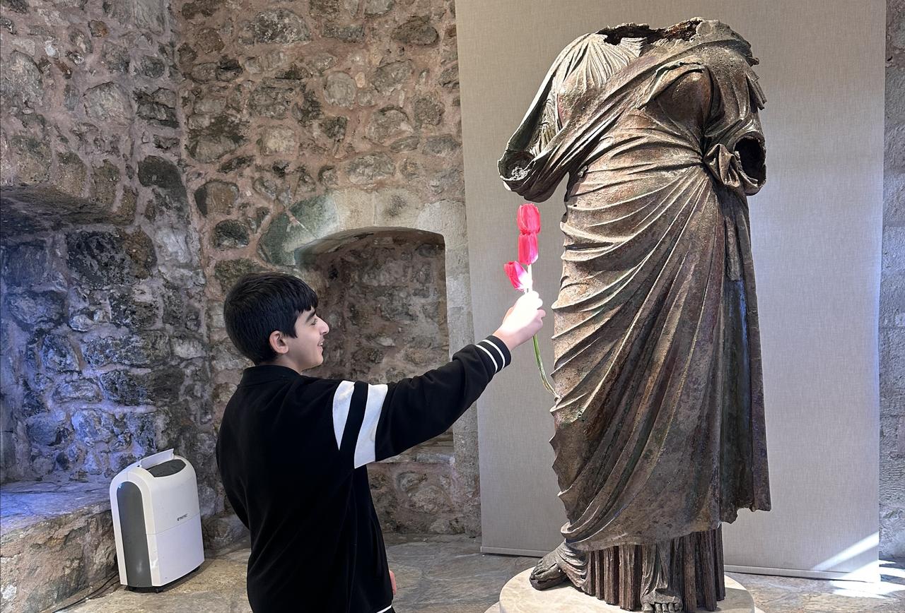 A middle school student symbolically interacts with a Roman-era bronze statue during an artificial intelligence-based educational project at the Marmaris Castle Museum in Mugla, Türkiye, Jan. 15, 2026. (AA Photo)