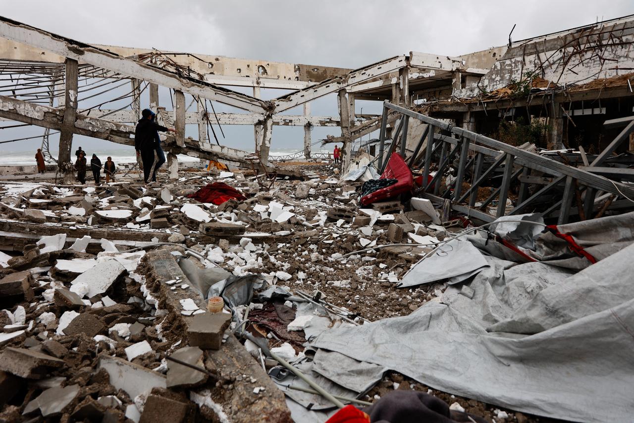 Palestinians stand amid the rubble inside a war-damaged building, parts of which collapsed on a windy winter day in Gaza City on Jan. 13, 2026. (AFP Photo)