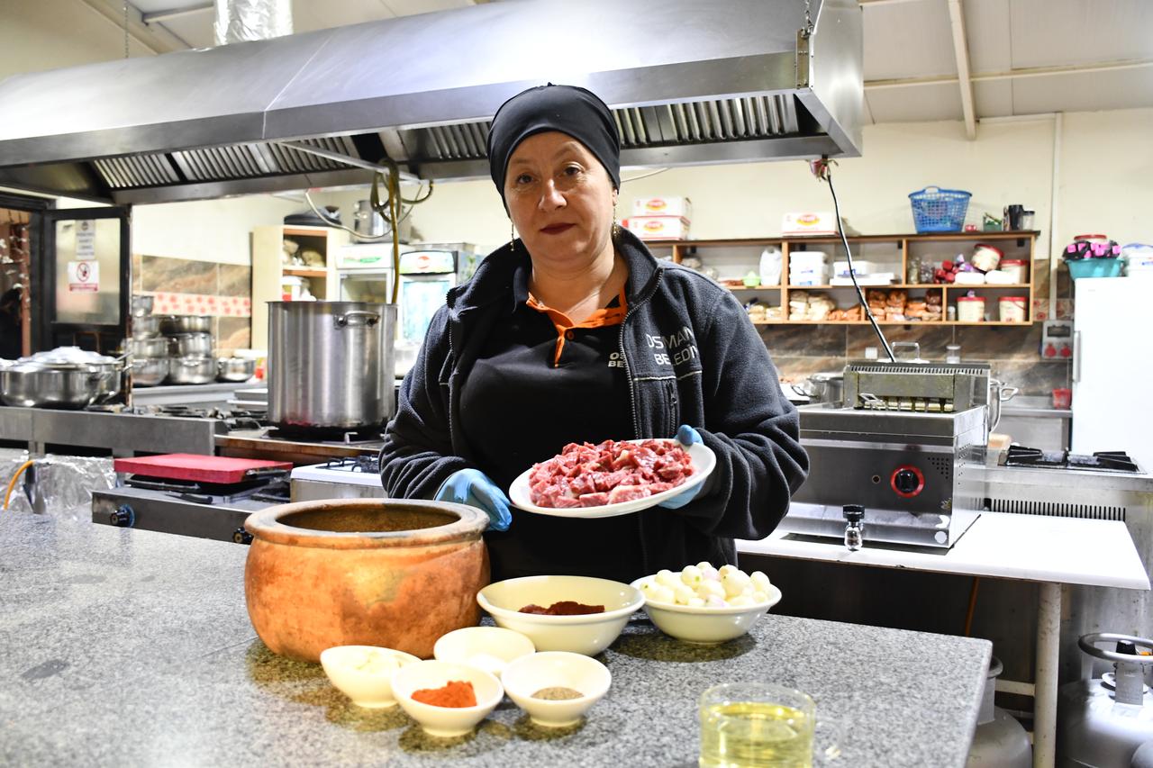 A cook presents raw beef prepared for papaz yahnisi alongside key ingredients, including pearl onions and spices, before the cooking process begins. (AA Photo)