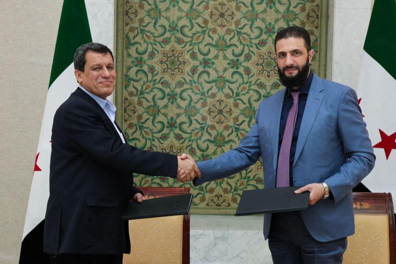 Syrias interim president Ahmed al-Sharaa (R) shaking the hand of YPG/SDFs so-called commander-in-chief Ferhat Abdi Sahin, also known as Mazloum Abdi after the signing of an agreement in the Syrian capital Damascus on March 10, 2025. (Photo by SANA / Handout / AFP)