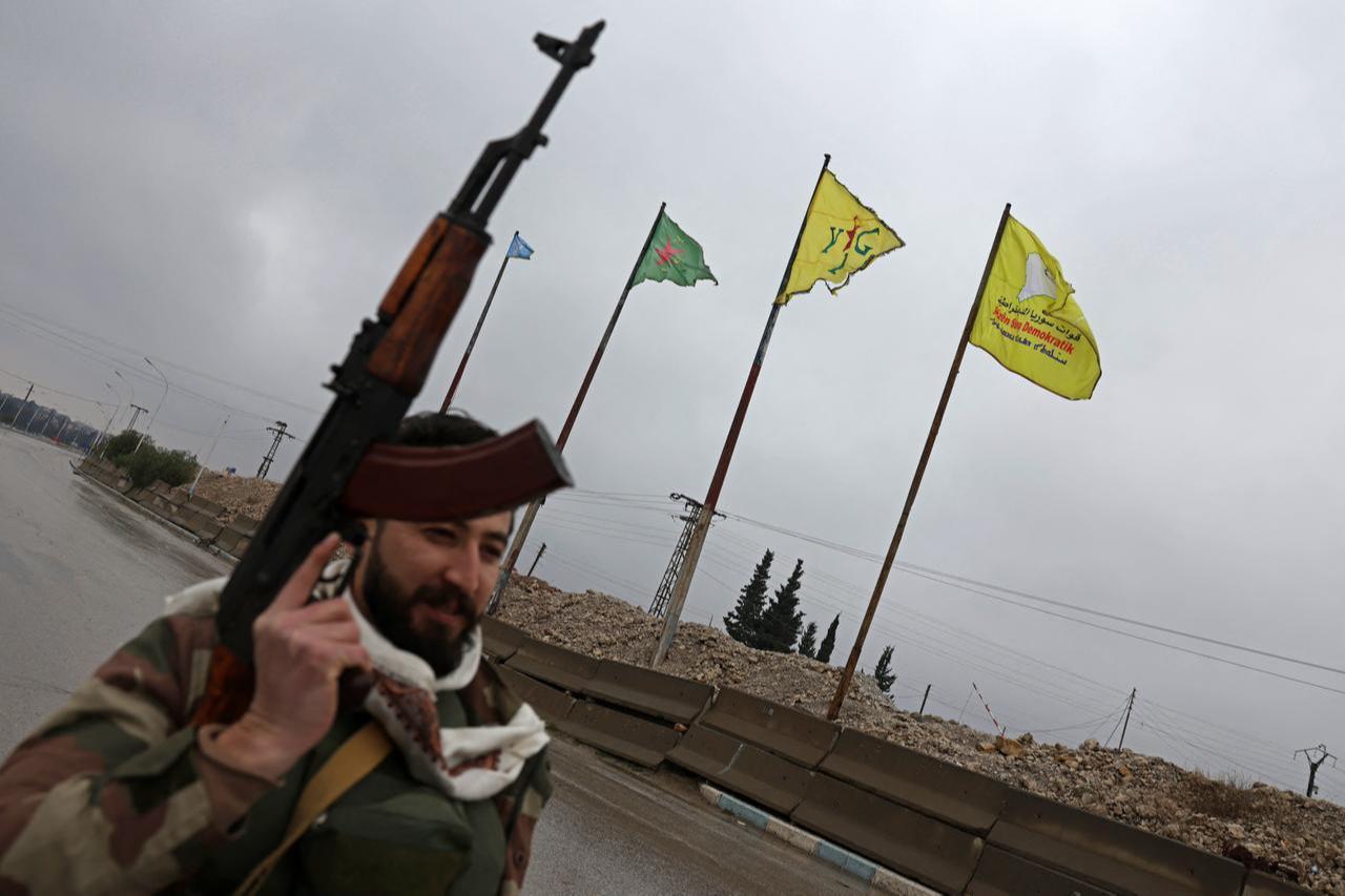 A Syrian army personnel walks past the YPG/SDF flag installed along a street in Tabqa, in Raqqa province, Syria, on January 18, 2026. (AFP Photo)
