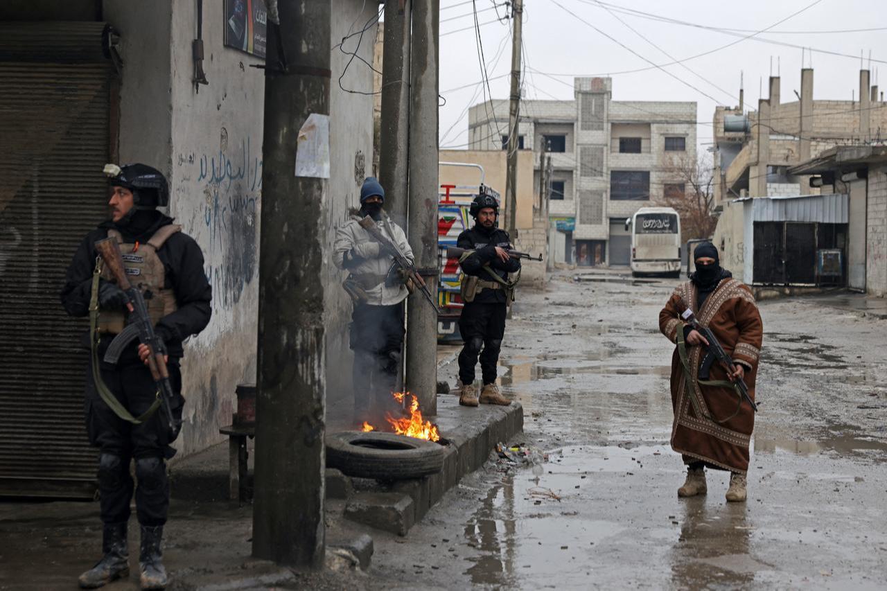 Syrian army personnel stand guard next to a burning tyre along a street in Tabqa, in Raqqa province, Syria, on January 18, 2026. (AFP Photo)