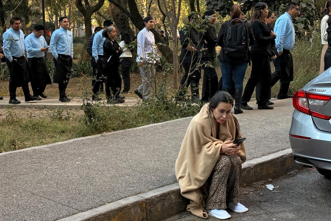 A guest uses a mobile phone opn the street after evacuating a hotel alongside staff during a 6.5 magnitude earthquake in Mexico City, on Jan. 2, 2026. (AFP Photo)