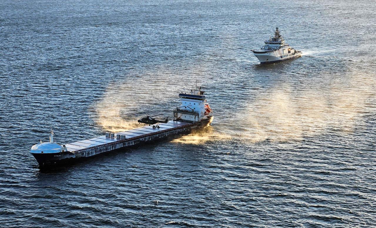A Border Guard helicopter and the Coast Guard patrol ship "Turva" (R) seizing the "Fitburg" vessel suspected of a subsea cable breach in the Gulf of Finland, 31 Dec. 2025. (Photo by Handout/various sources/AFP)