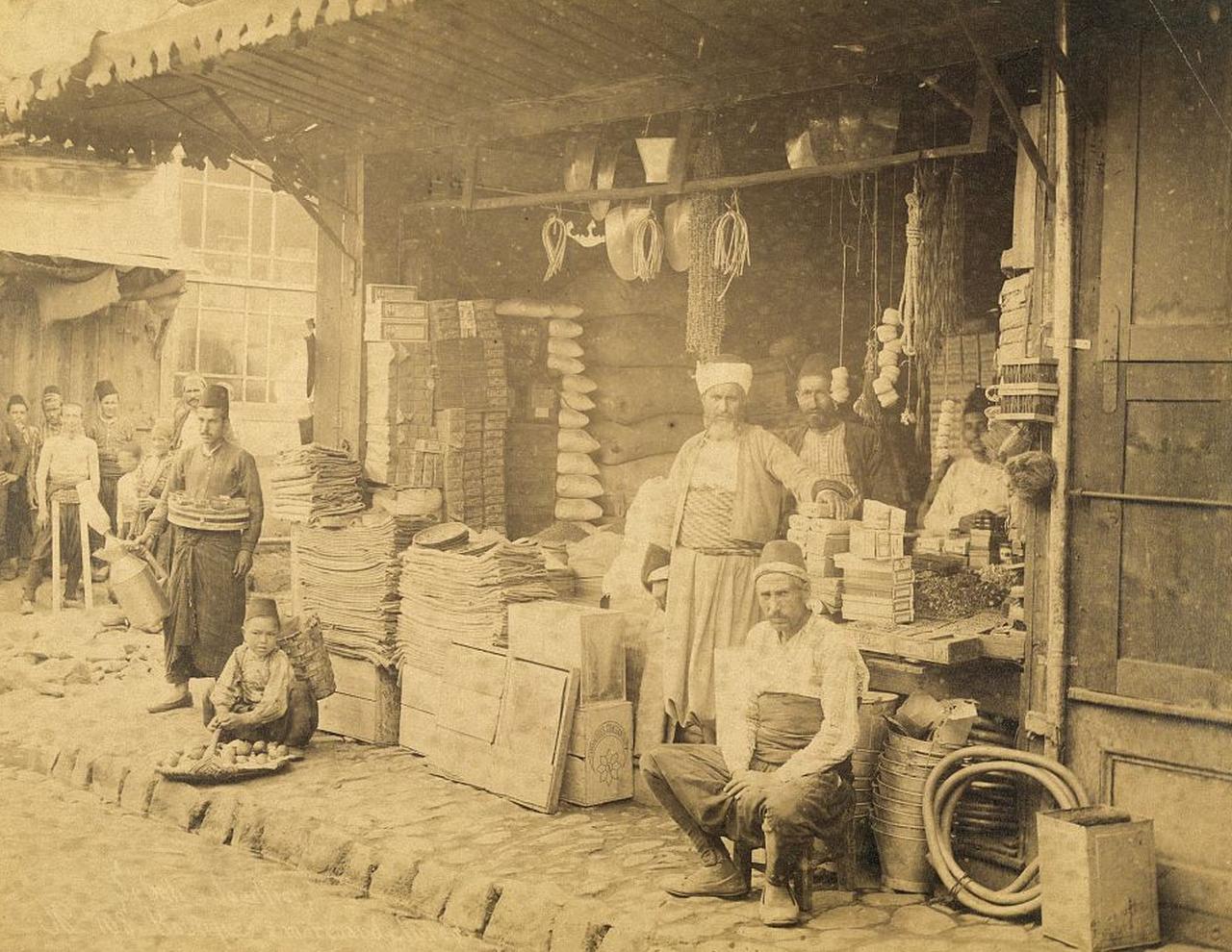 Photograph shows merchants with wares in shop which is open to the street, Istanbul, Türkiye, 19th century. (Photo via Sebah & Joaillier)