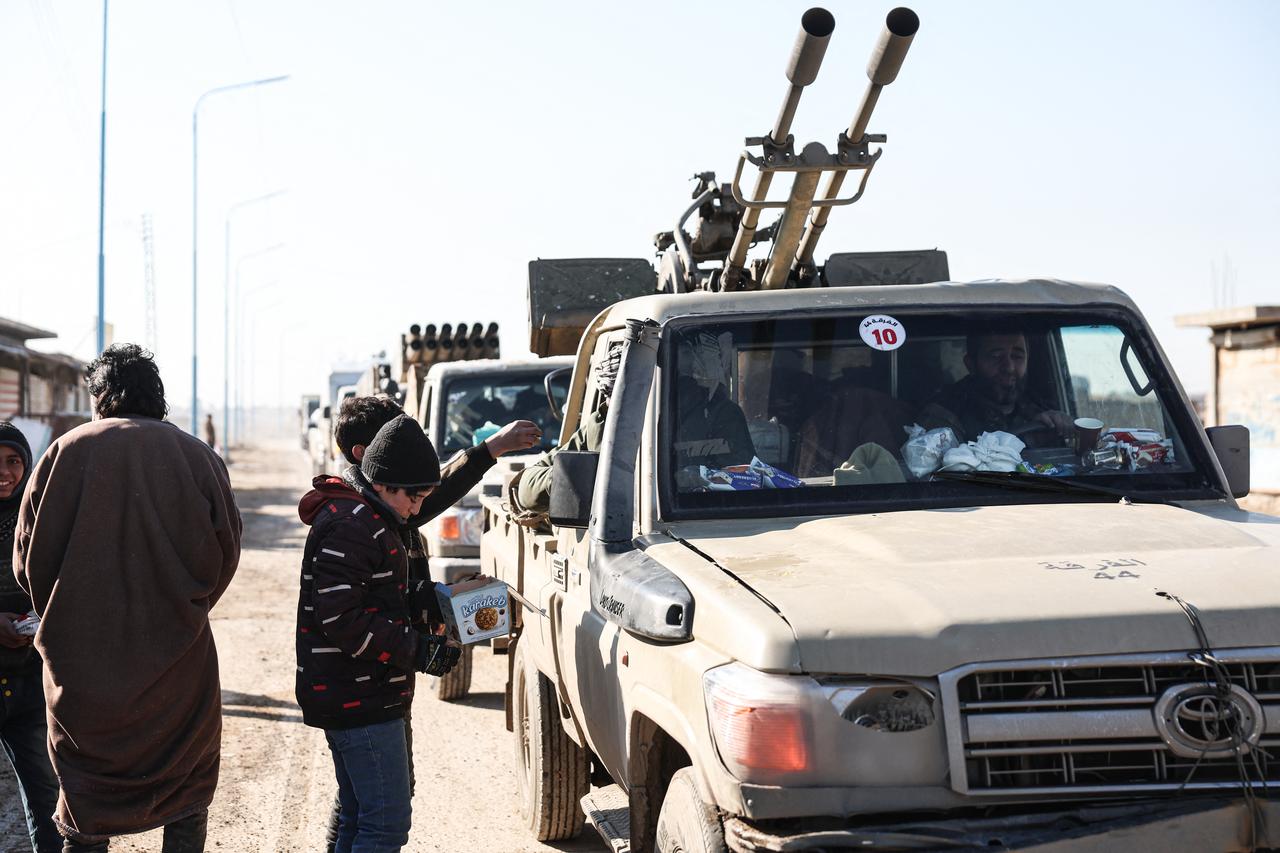 Residents give out sweets to passing Syrian government forces as they enter the city of al-Shaddadi, south of the city of Hasakah, in northeastern Syria January 20, 2026. (AFP Photo)