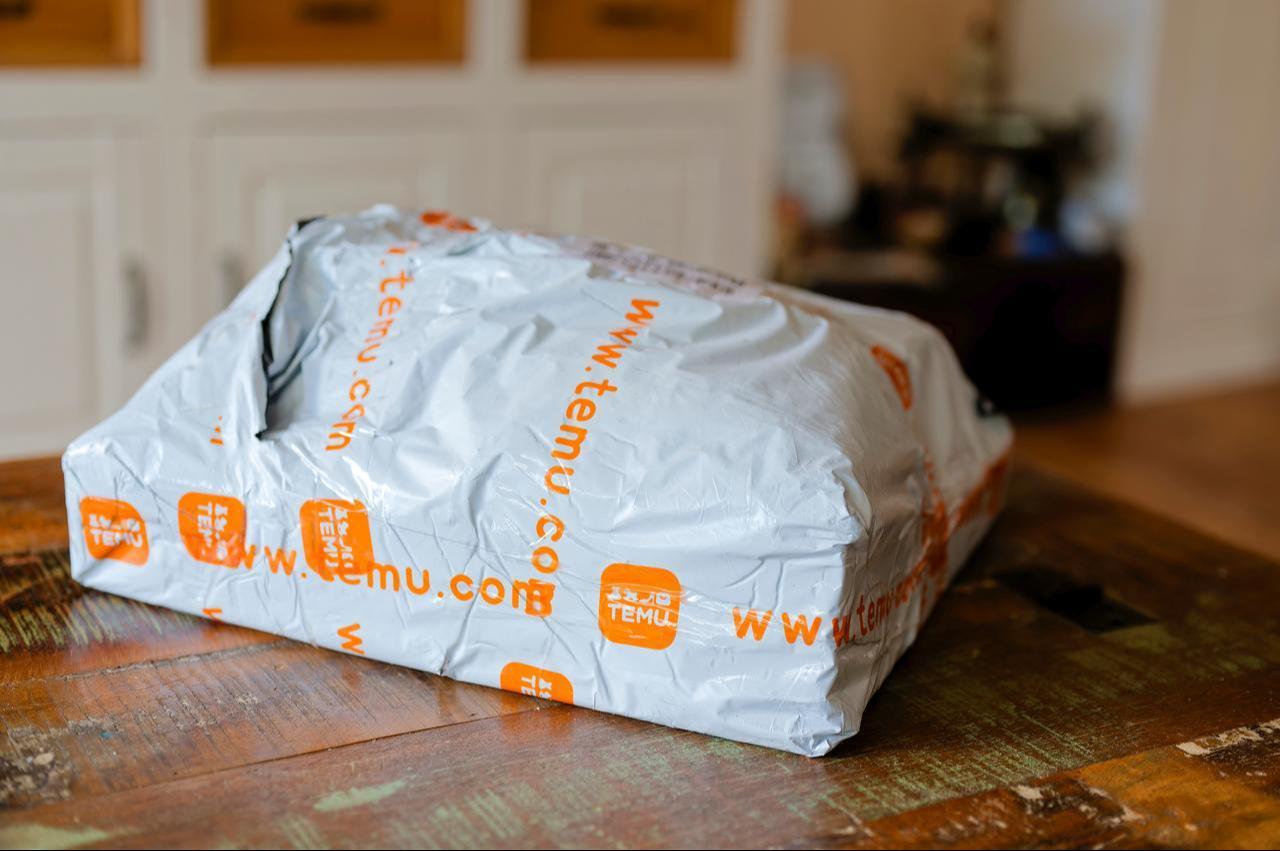 A delivery package from Chinese e-commerce platform Temu is seen on a wooden table. (Adobe Stock Photo)