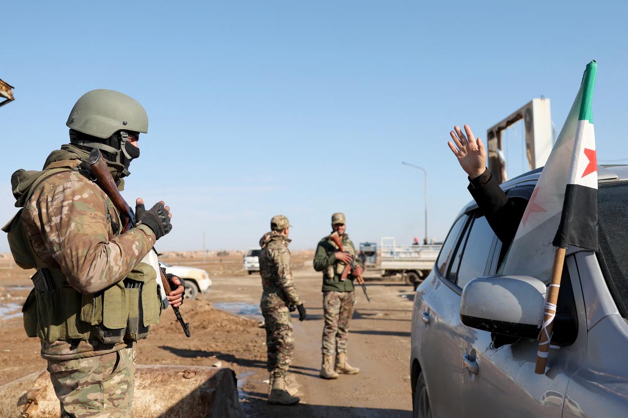 A residents waves as Syrian government forces man a checkpoint after entering the city of al-Shaddadi south of the city of Hasakah in Syria, Jan. 20, 2026. (AFP Photo)