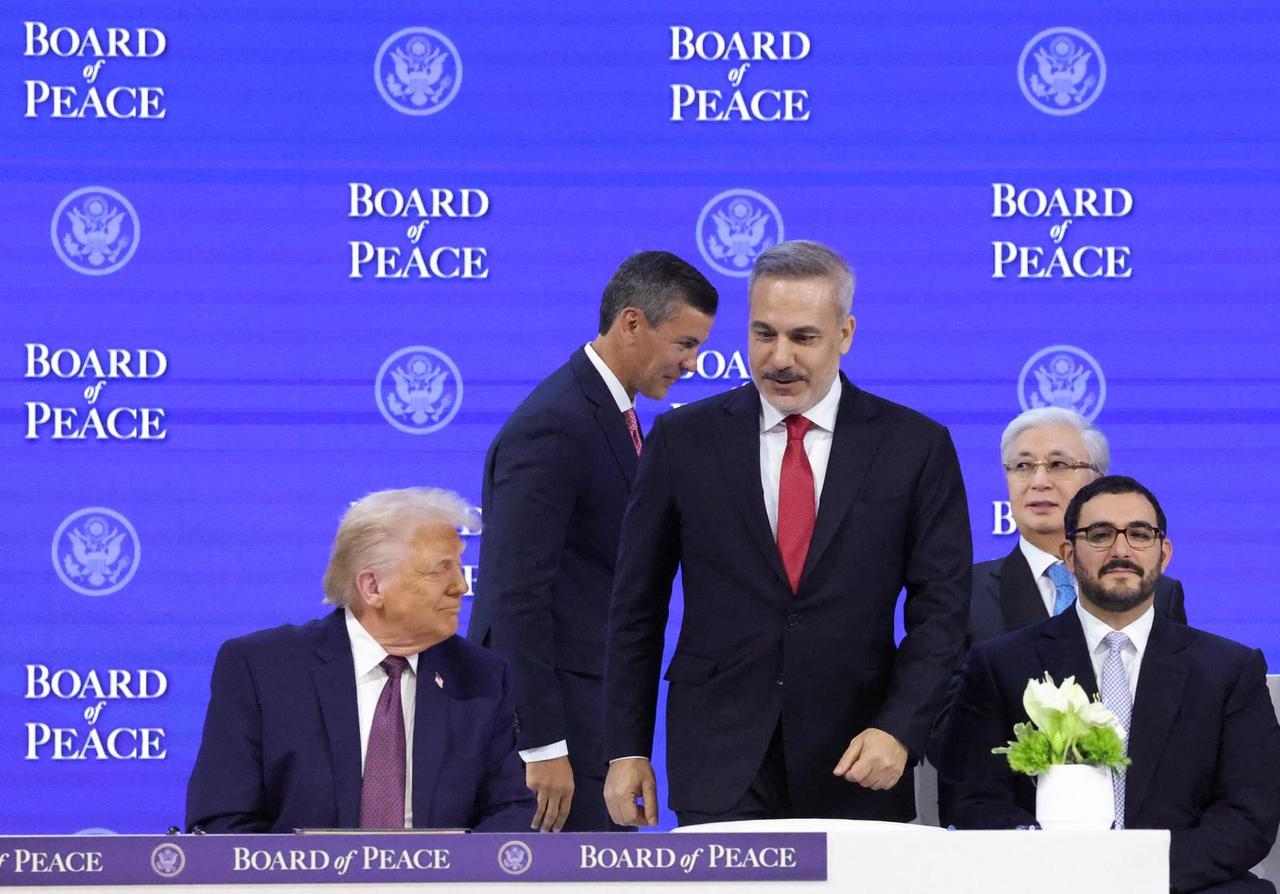 U.S. President Donald Trump (L), and Turkish Foreign Minister Hakan Fidan (3rd L) sign the charter of the Board of Peace during the 56th World Economic Forum in Davos, Switzerland on January 22, 2026. (Turkish Foreign Ministry Handout / AA Photo)