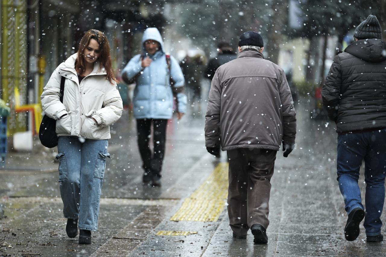 People walk on the streets during snowfall in capital Ankara, Türkiye on January 22, 2026. (AA Photo)