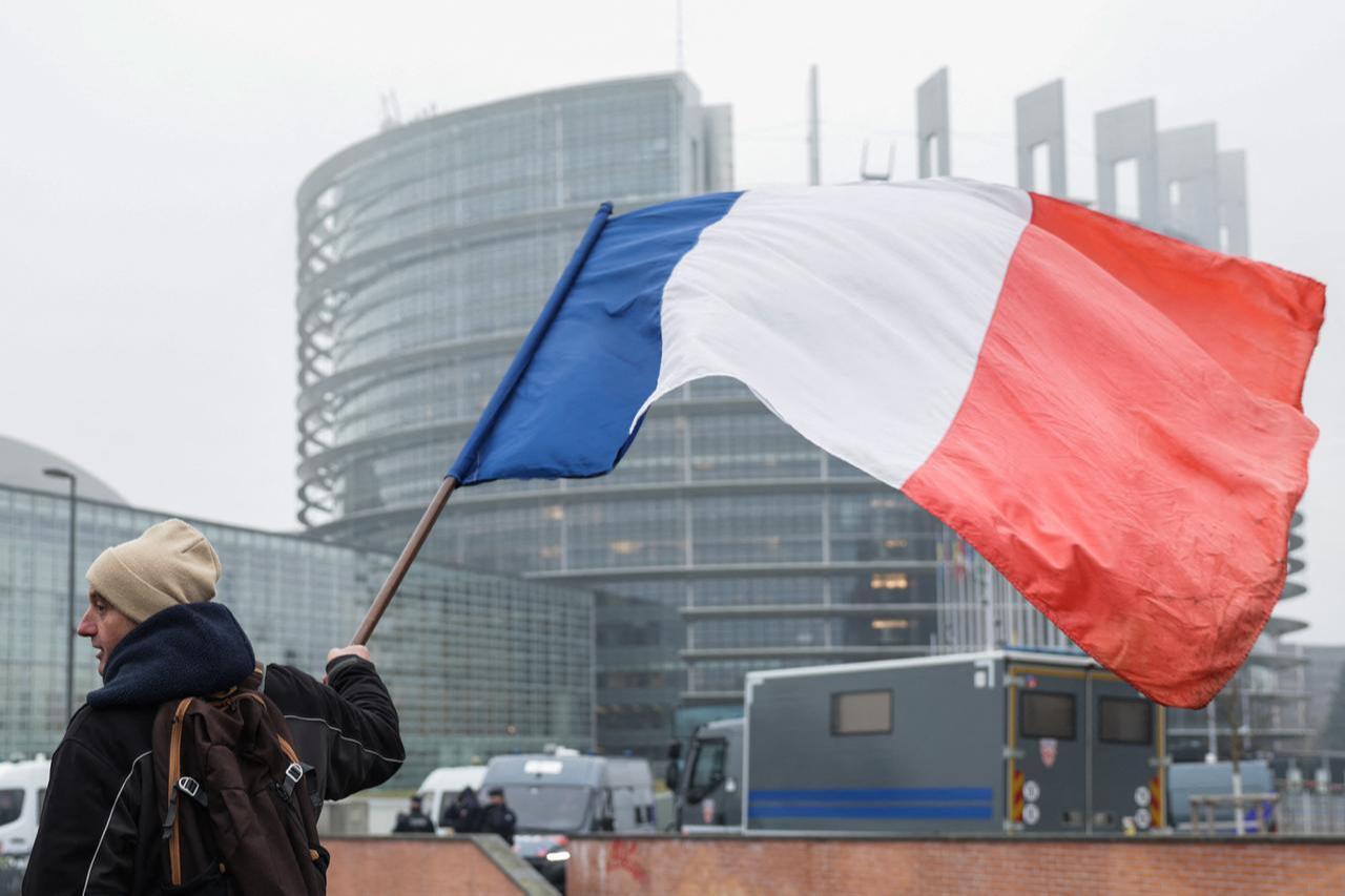 A demonstrator holds a French flag with the EU Parliament building in the background, in Strasbourg, Jan. 21, 2026. (AFP Photo)