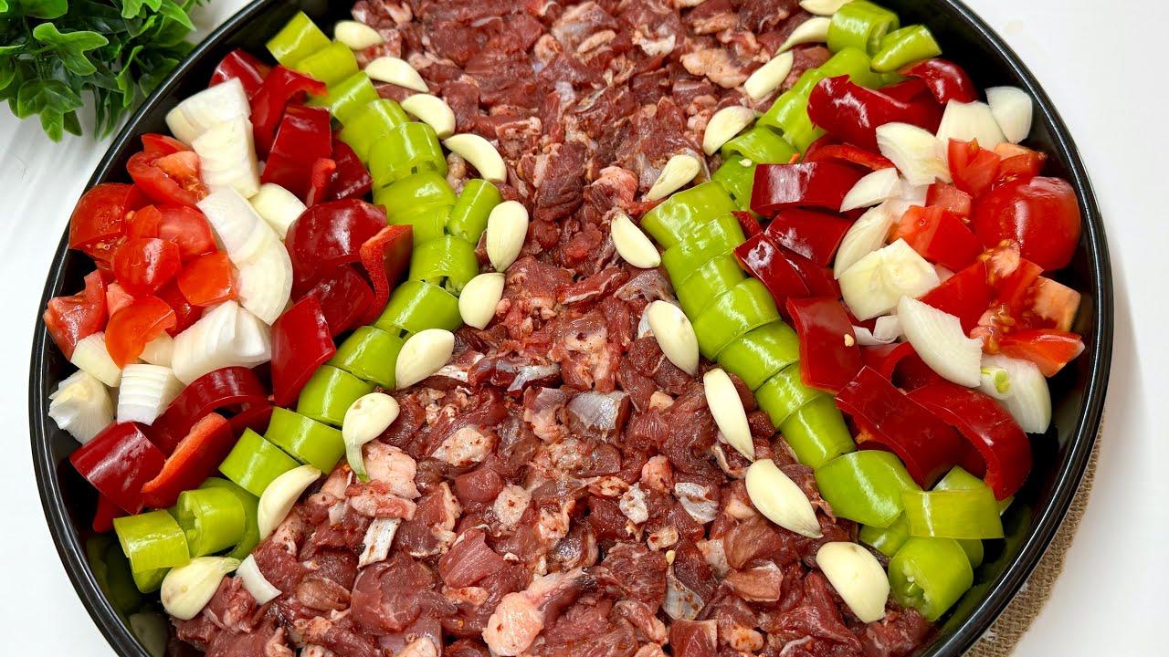 The main ingredients of Eli Bogrunde, including marinated lamb, tomatoes, green peppers, garlic and optional potatoes, are arranged side by side in a baking tray before cooking. (Photo via YouTube/@CicekinTarifleri)