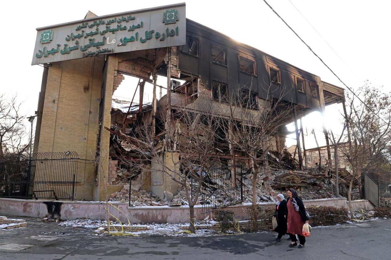 Women walking past a government building that was burnt during recent public protests, in Tehran, Iran on January 21, 2026. (AFP Photo)