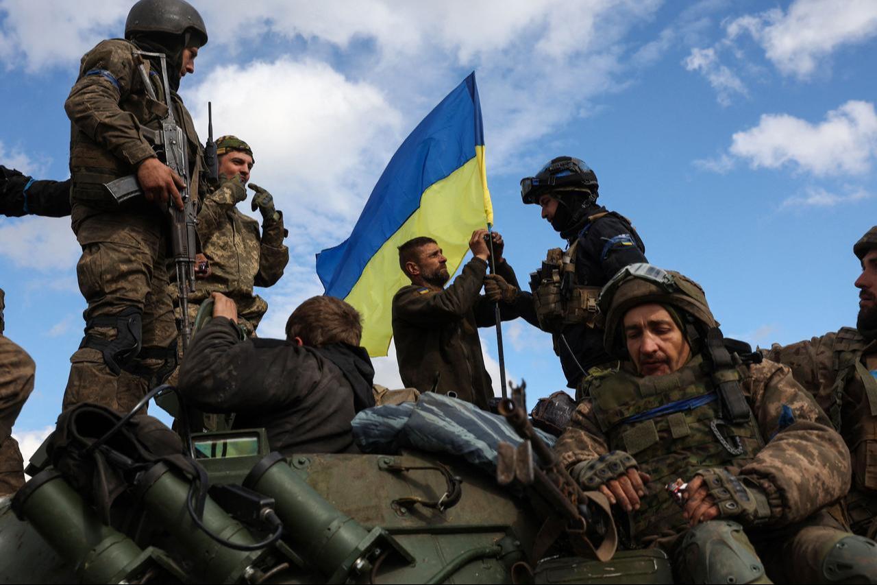 Ukrainian soldiers adjust a national flag atop a personnel armoured carrier on a road near Lyman, Donetsk region, Ukraine on October 4, 2022. (AFP Photo)
