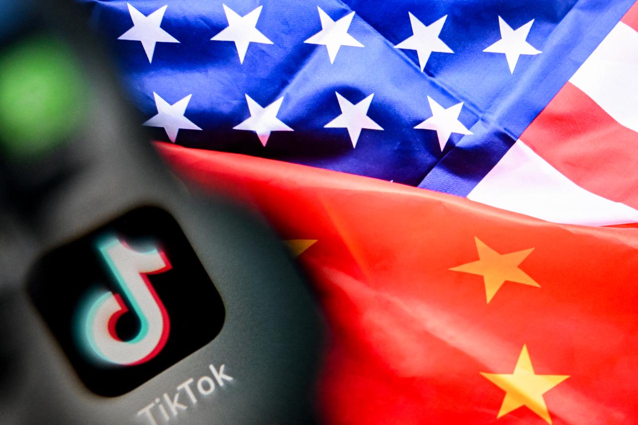 The photo shows the Chinese social networking service TikTok's logo on a smartphone screen (L) and a US and China flag illustration on a laptop screen in Frankfurt am Main, western Germany,  on April 10, 2025. (AFP File Photo)