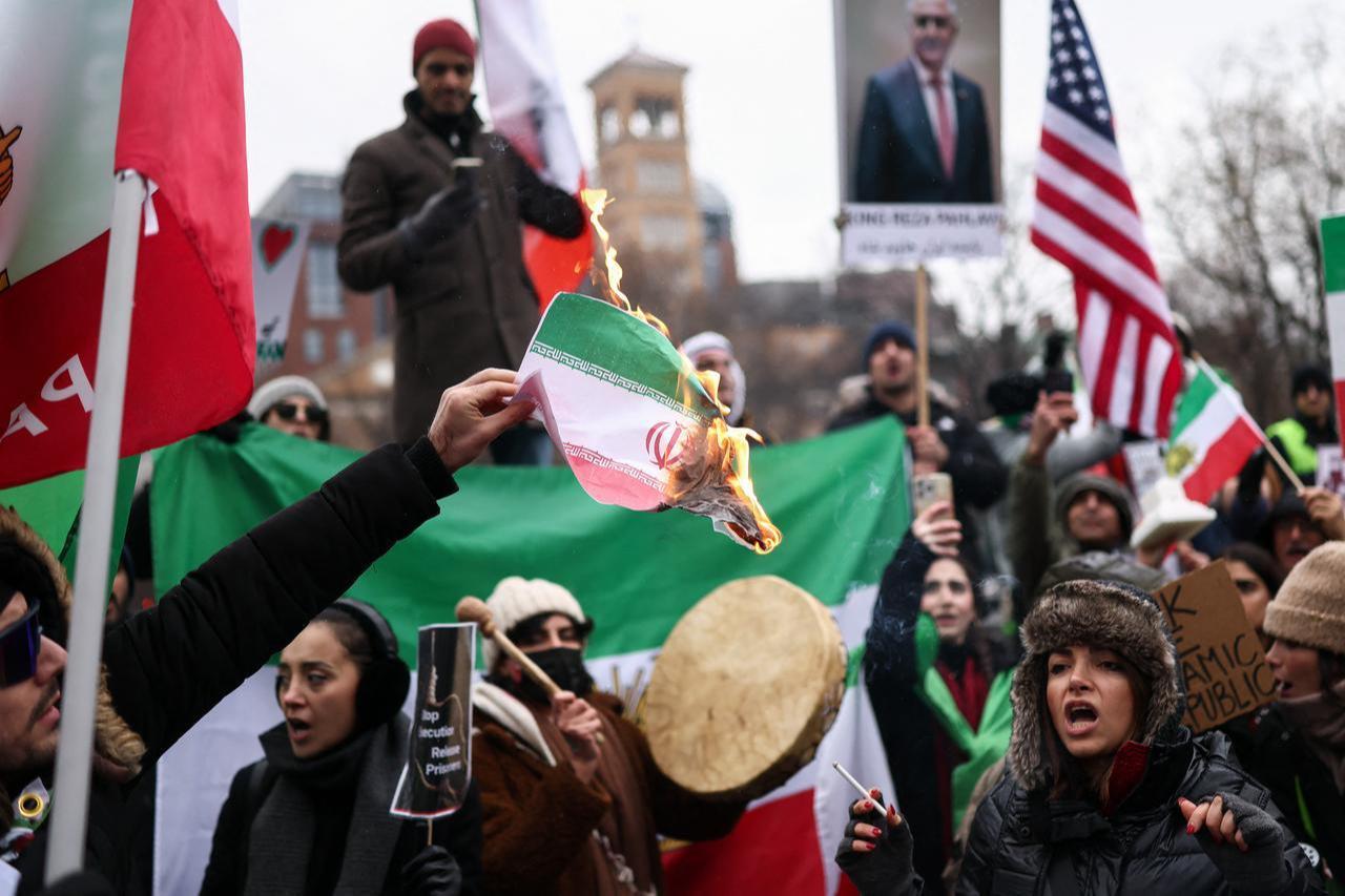 A man burns an Iranian flag while people sing and shout during a rally in support of the Iranian people in New York, US on Jan. 18, 2026. (AFP Photo)
